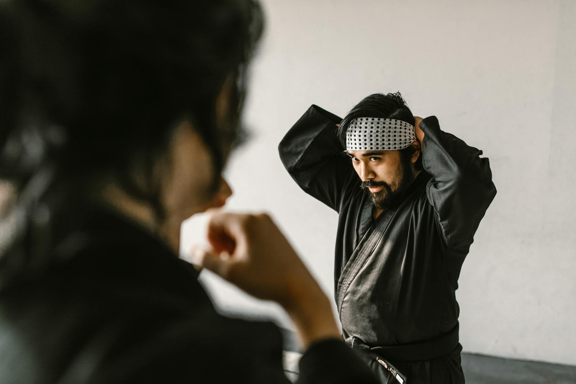 Portrait of a martial artist in a gi preparing for training indoors, exuding focus and determination.