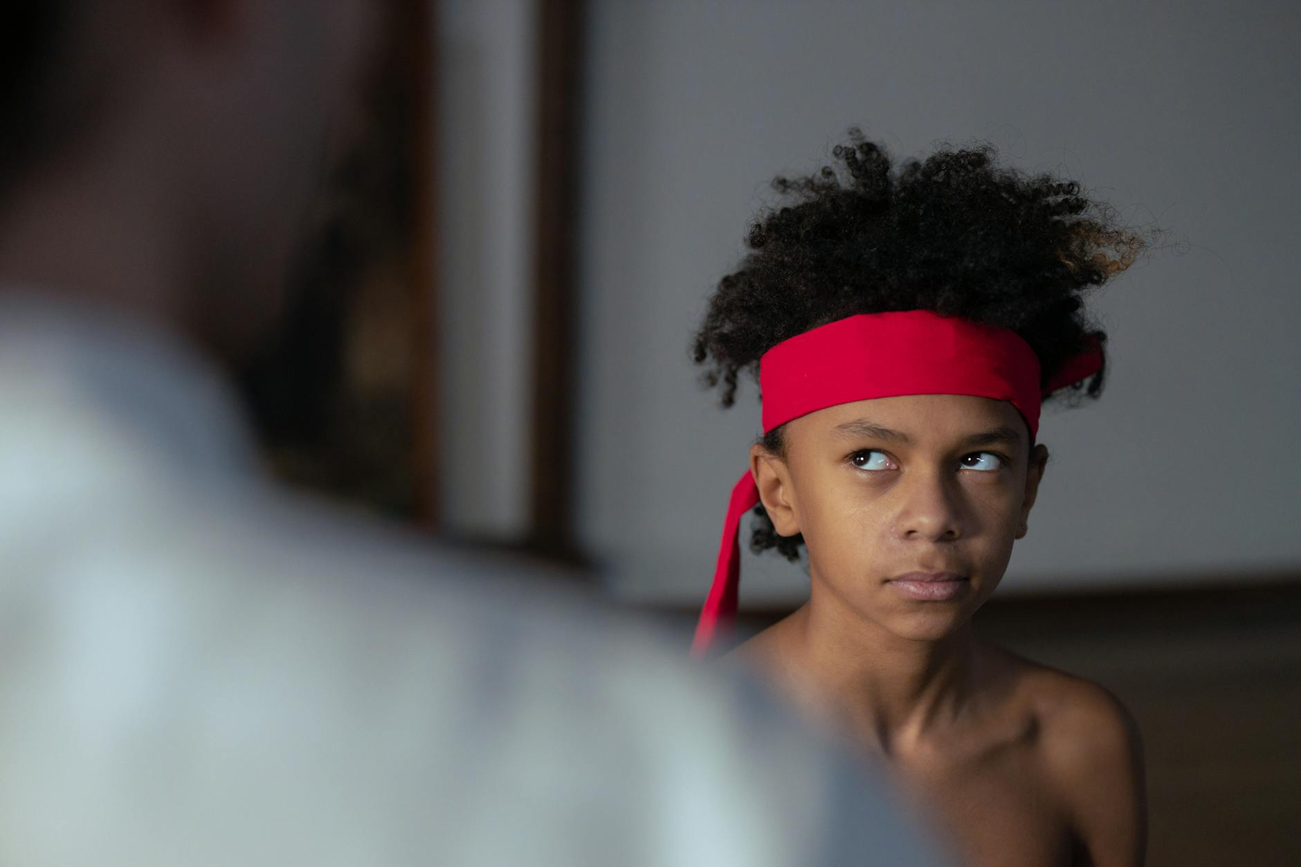 A young martial artist with red headband showing focus indoors. Ideal for sports themes. Martial Arts Builds Focus